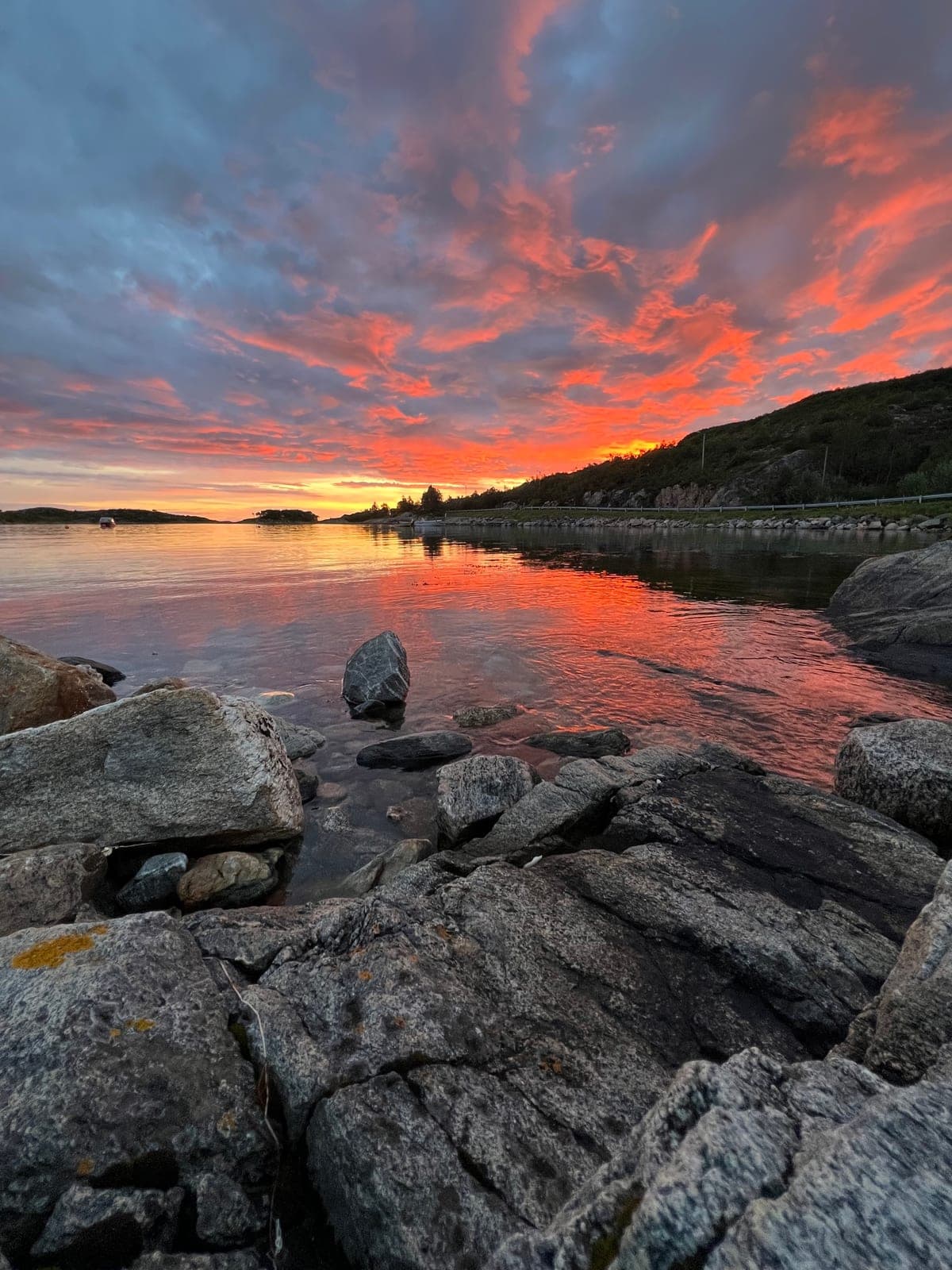 A red and orange sky burning out over the cove, the rocks in the foreground