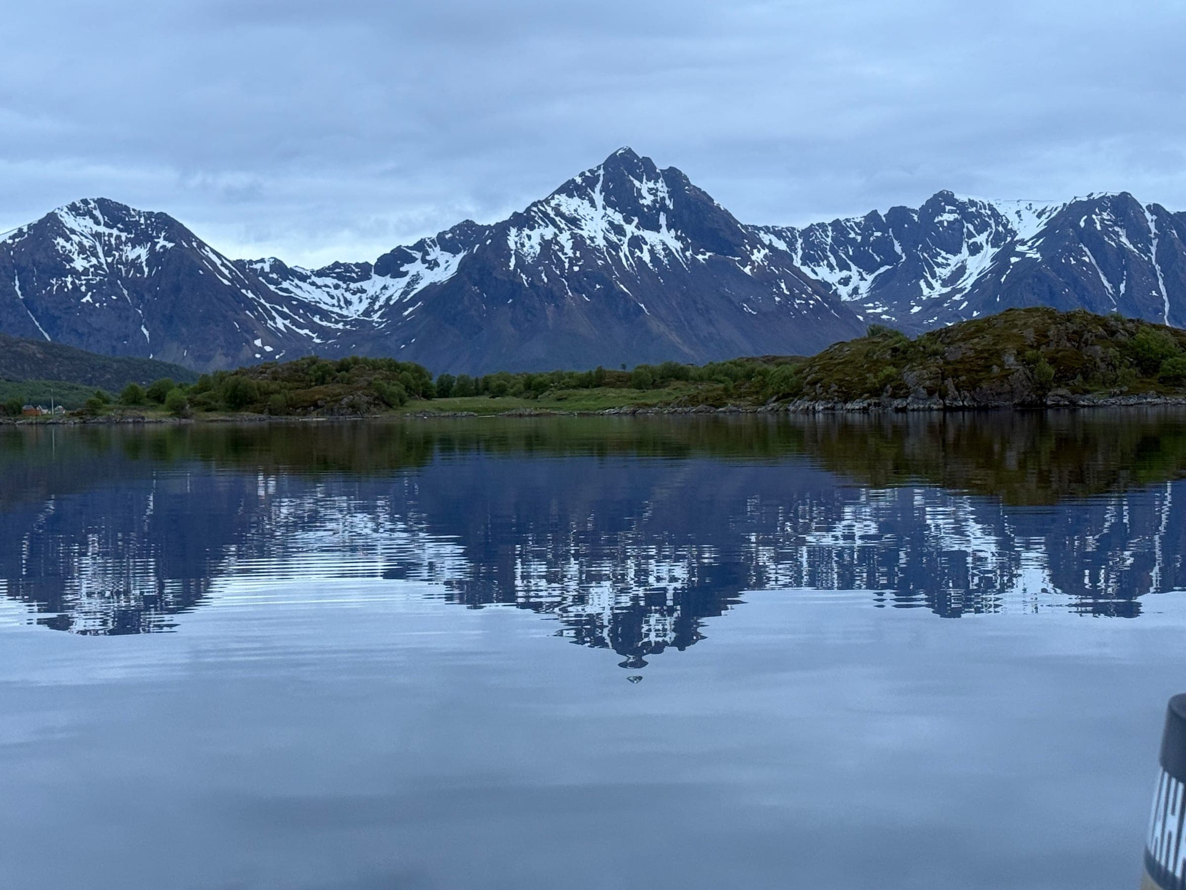 Snow-streaked peaks mirrored in still water at blue hour